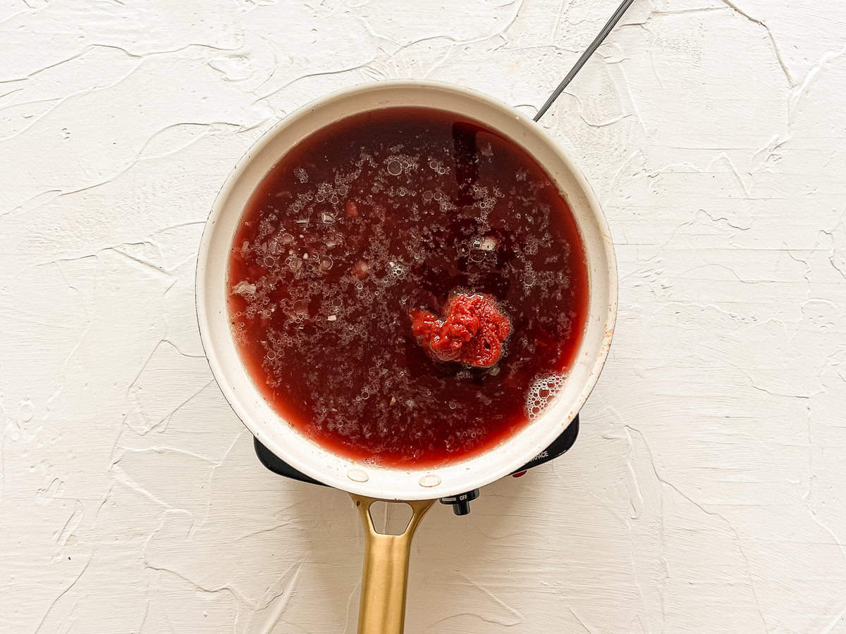 Tomato paste dumped into a skillet of broth and sauteed onions.