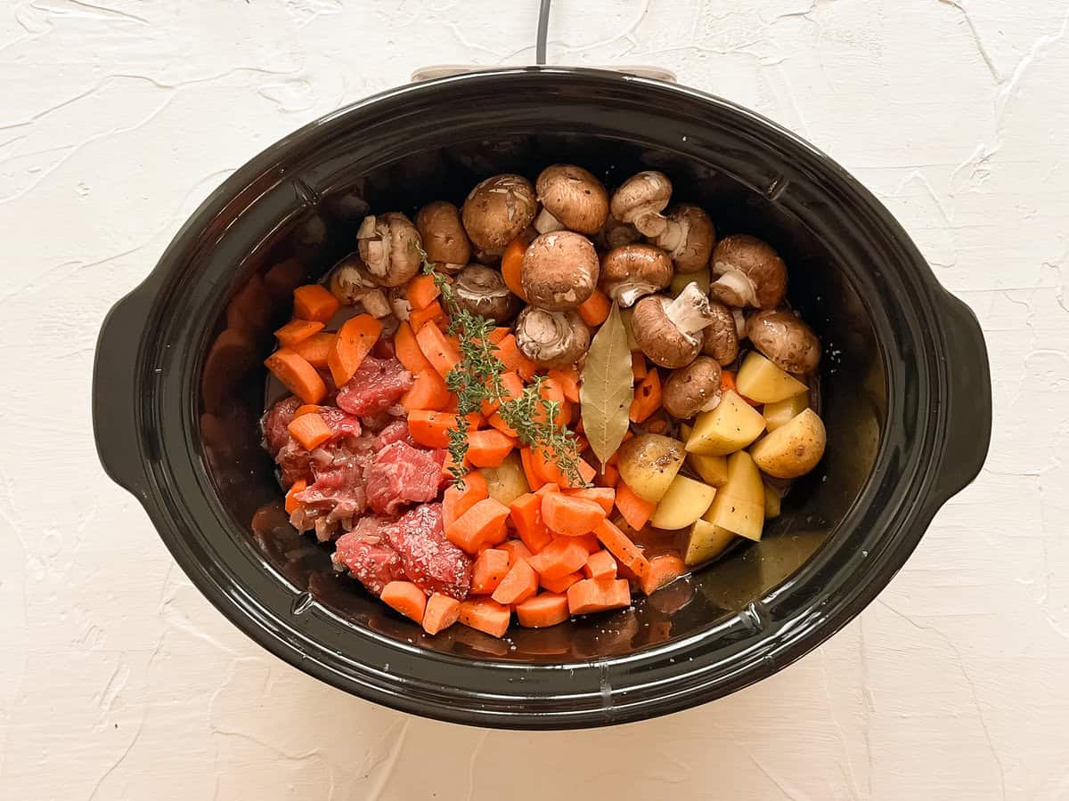 Raw ingredients for beef bourguignon in a slow cooker ready to cook.