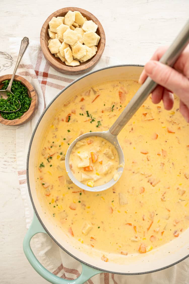 Potato corn chowder being ladled out of a pot.