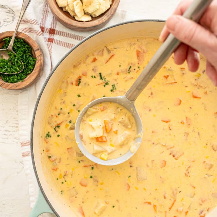 Potato corn chowder being ladled out of a pot.