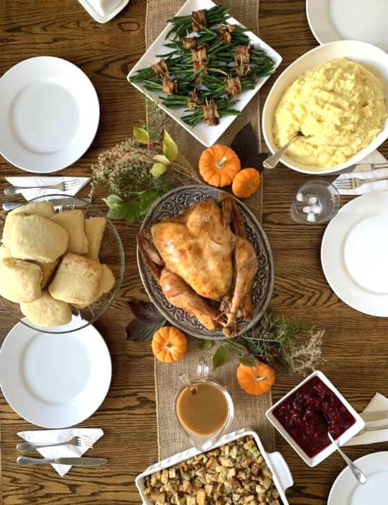 Thanksgiving table with turkey, mashed potatoes, biscuits, and more.