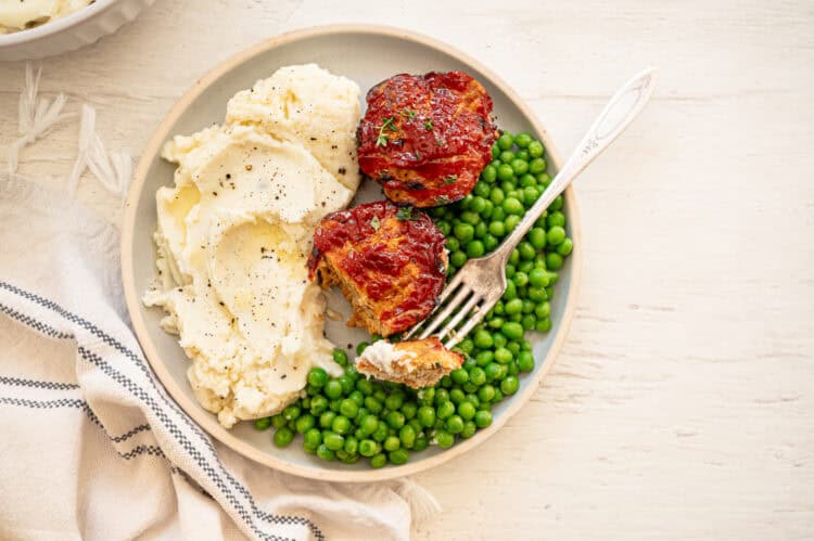 Turkey meatloaf muffins, mashed potatoes, and peas on a plate.