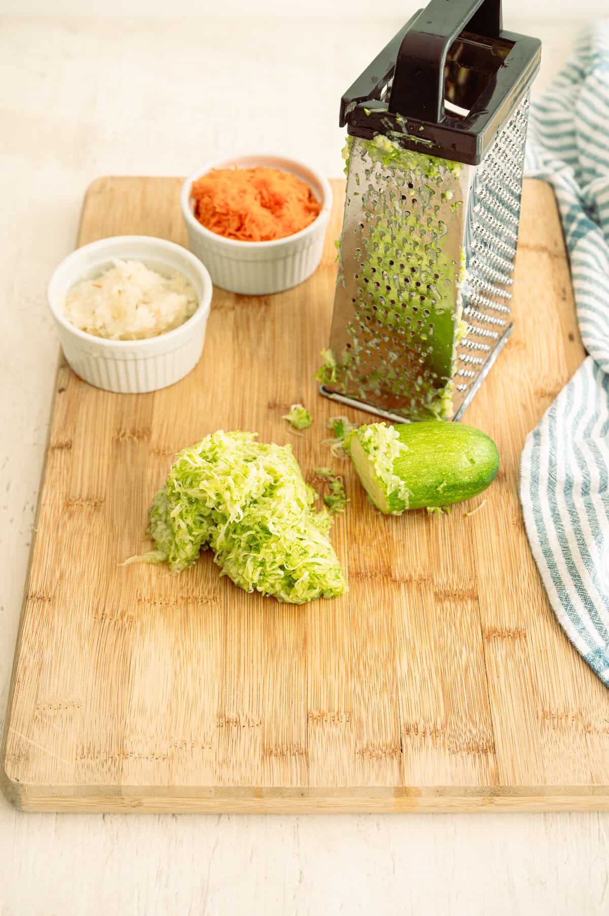 Zucchini being shredded on a box grater.