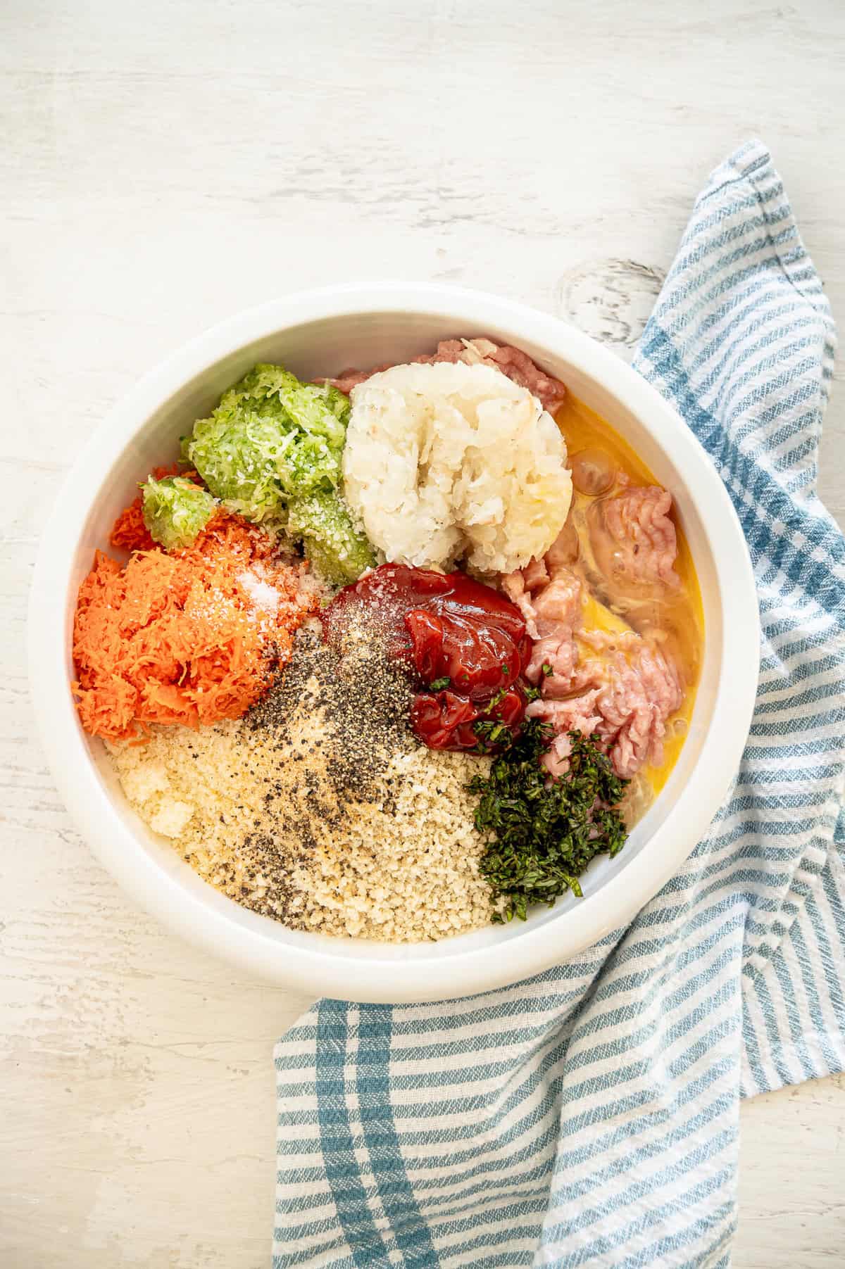 All the ingredients for turkey meatloaf muffins in a bowl ready to be mixed.