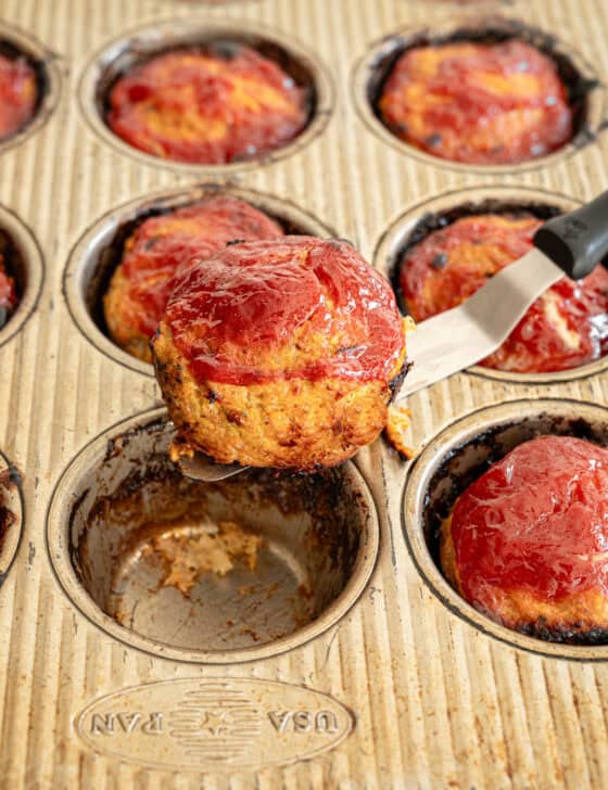 A turkey meatloaf muffin being lifted from the muffin tin ready to serve.