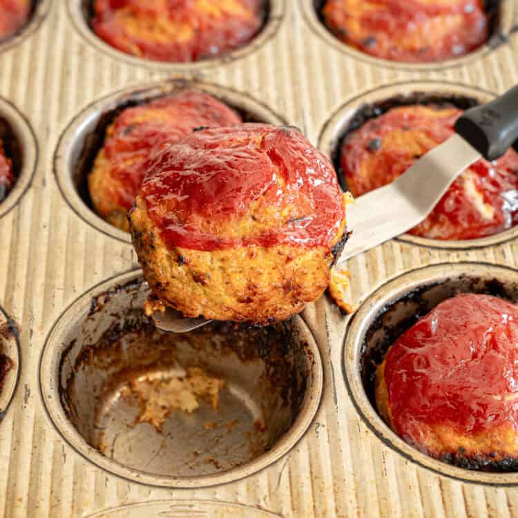 A turkey meatloaf muffin being lifted from the muffin tin ready to serve.