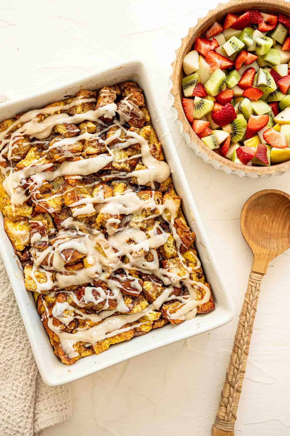 A 9x12 baking dish of cinnamon roll casserole and a bowl of fruit salad.