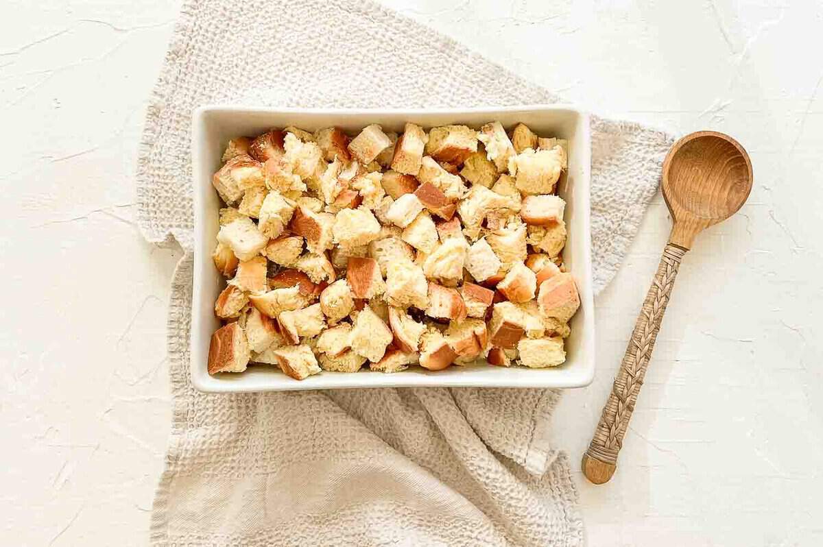 Pieces of brioche bread in a 9x12 casserole as the first layer of cinnamon roll casserole.