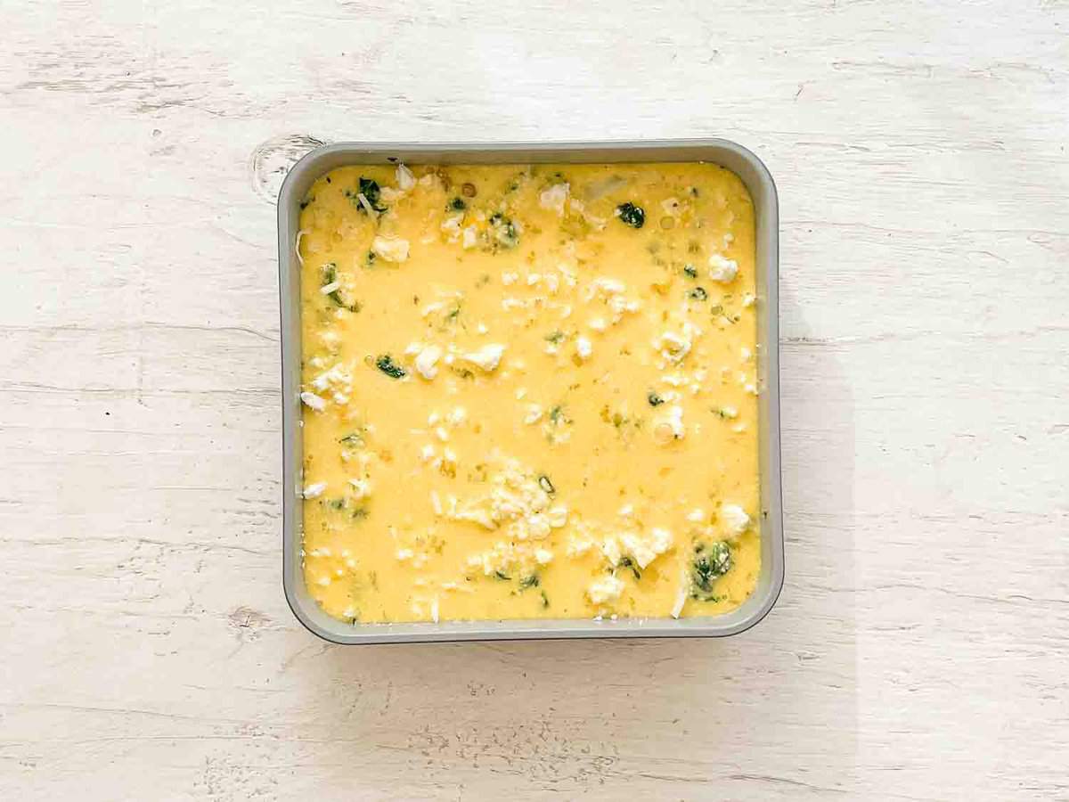 A baking dish with Mediterranean breakfast casserole ingredients ready for the oven.