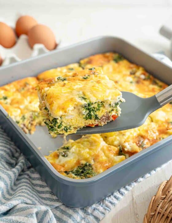 A spatula lifting a slice of Mediterranean high protein low carb breakfast casserole from the baking dish.