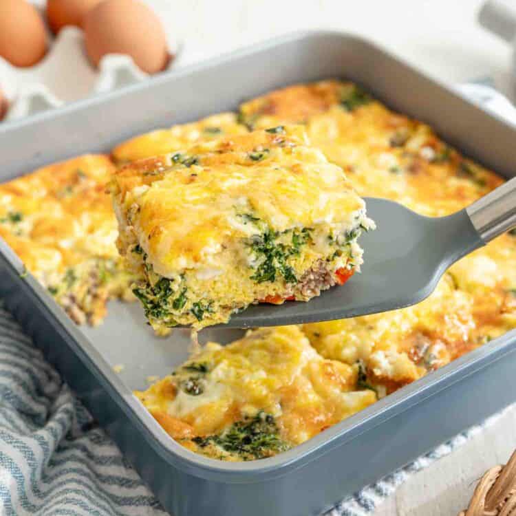 A spatula lifting a slice of Mediterranean high protein low carb breakfast casserole from the baking dish.