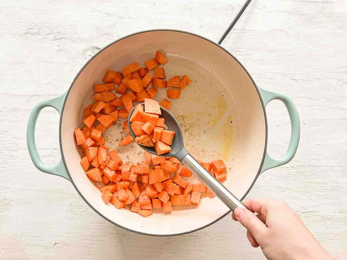 Sweet potatoes being sauteed in a ceramic pan.