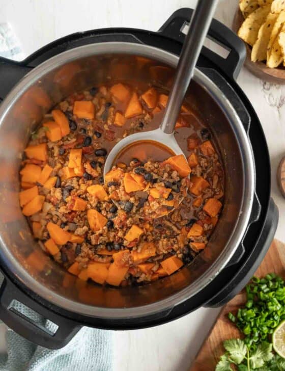 A spoon lifting a serving of turkey and sweet potato chili out of an Instant Pot.