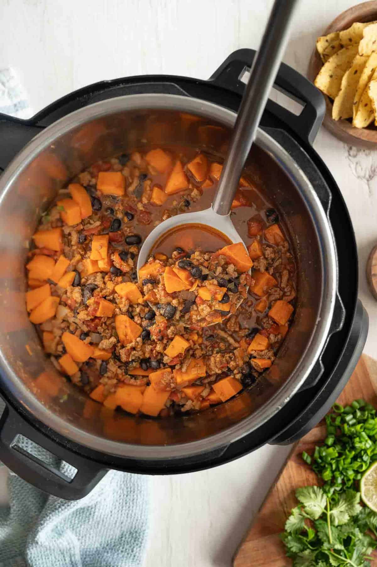 A spoon lifting a serving of turkey and sweet potato chili out of an Instant Pot.