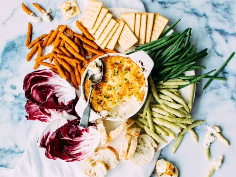 Creamy crab dip in the center with crackers and fresh veggies around it.