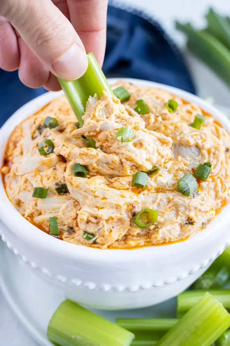 Crockpot buffalo chicken dip with a celery stick being dipped into it.