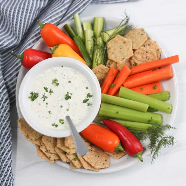 A plate of fresh veggies and crackers with a bowl of homemade ranch dip.