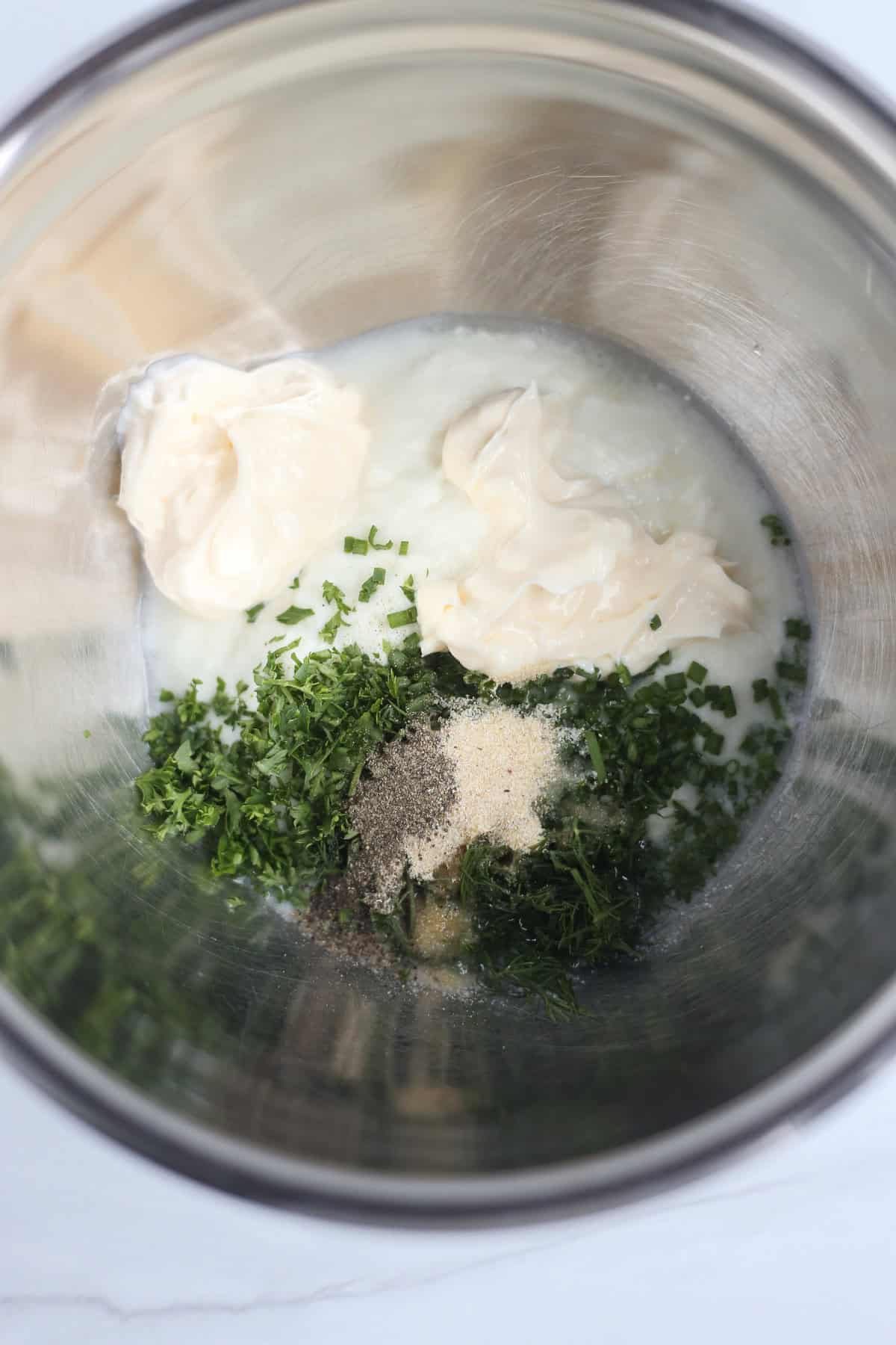 Ingredients for homemade ranch dip in the bowl of a food processor.