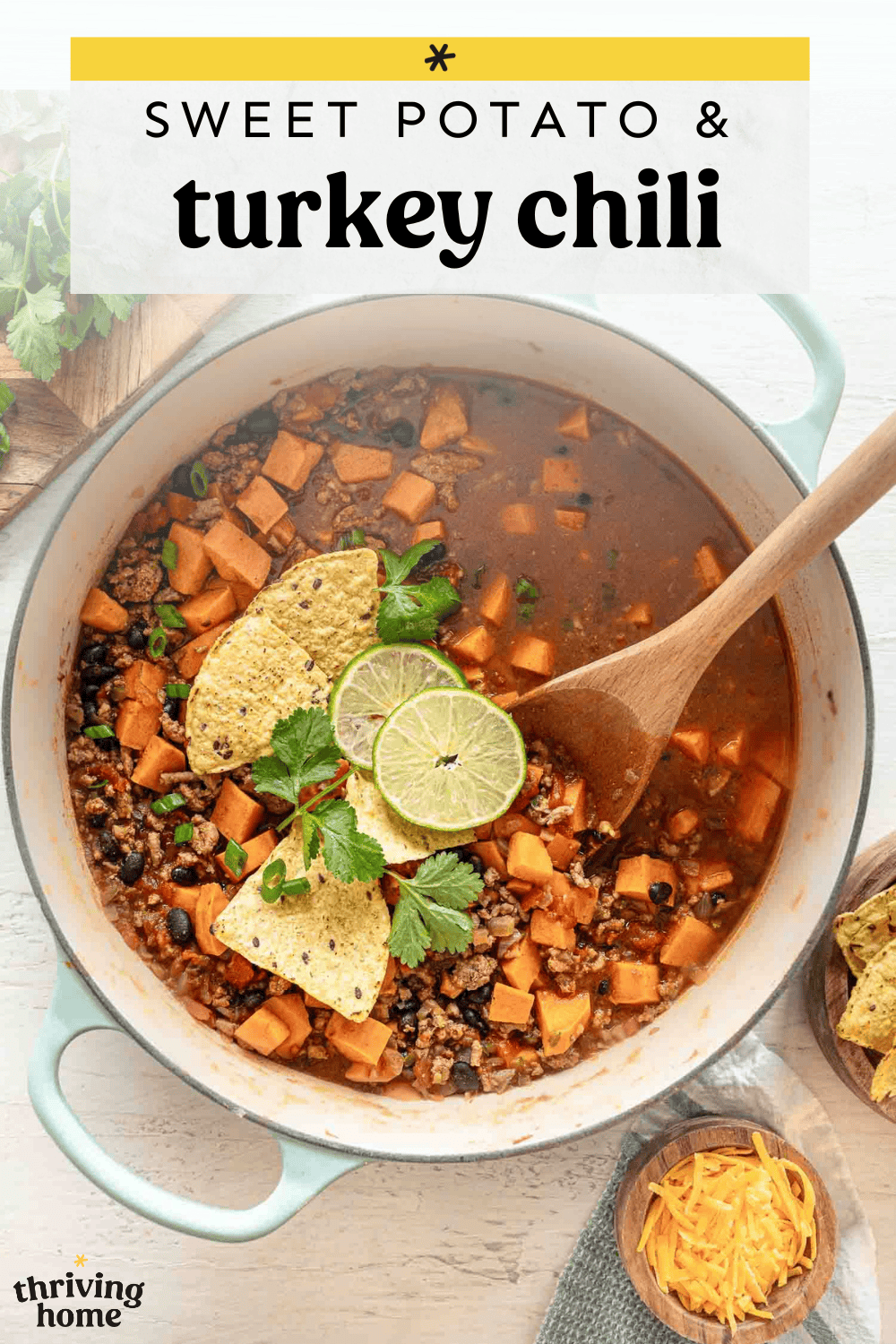 Easy Turkey Chili with sweet potatoes in a pot with lime slices, tortilla chips, and fresh parsley on top.