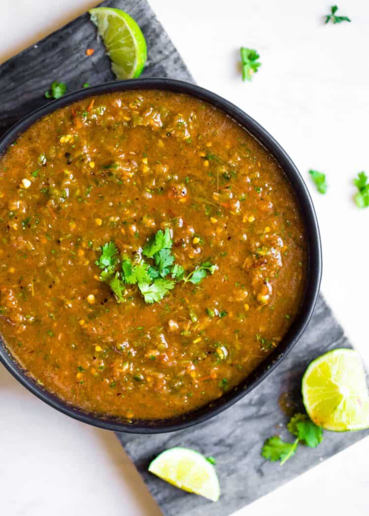 Homemade salsa in a black bowl with fresh cilantro on top.