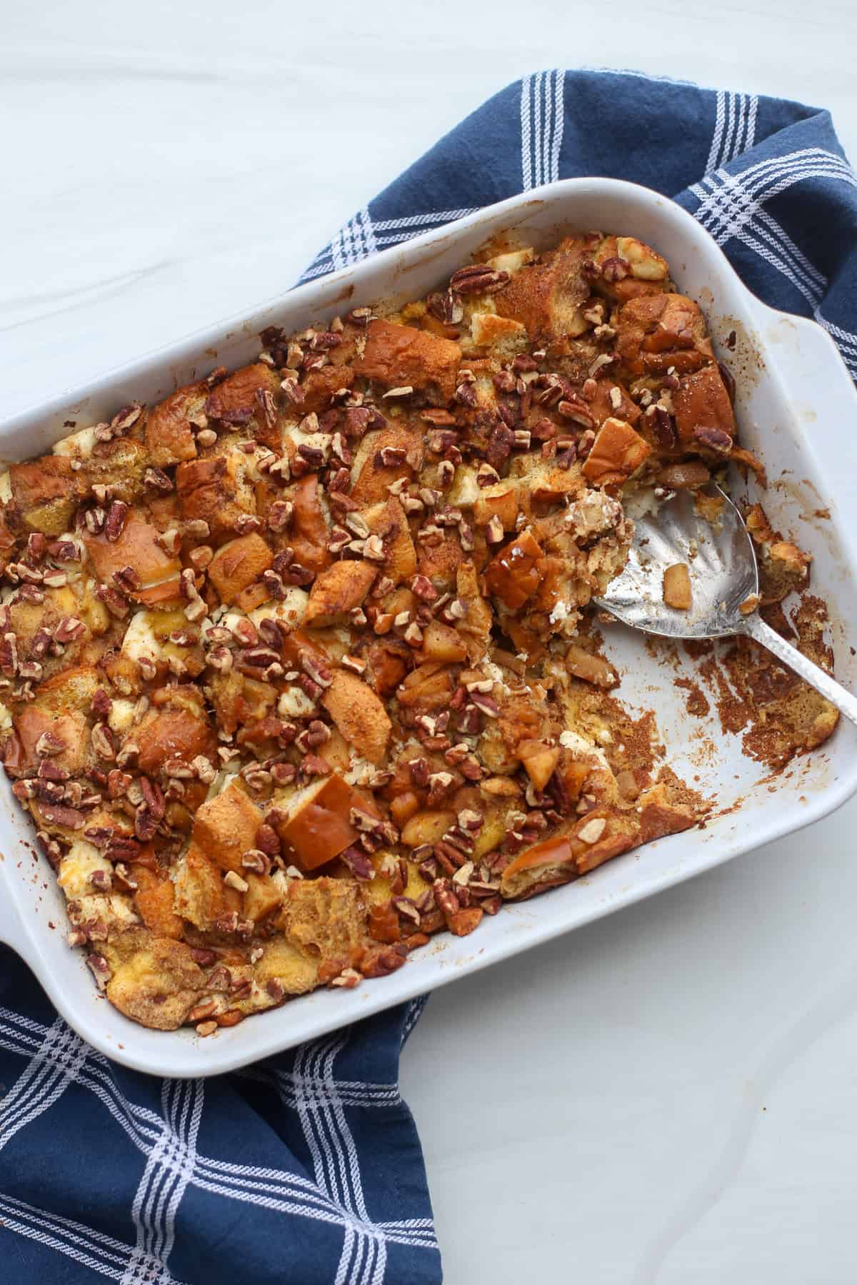 Apple cinnamon french toast casserole in a baking dish with a serving taken out.