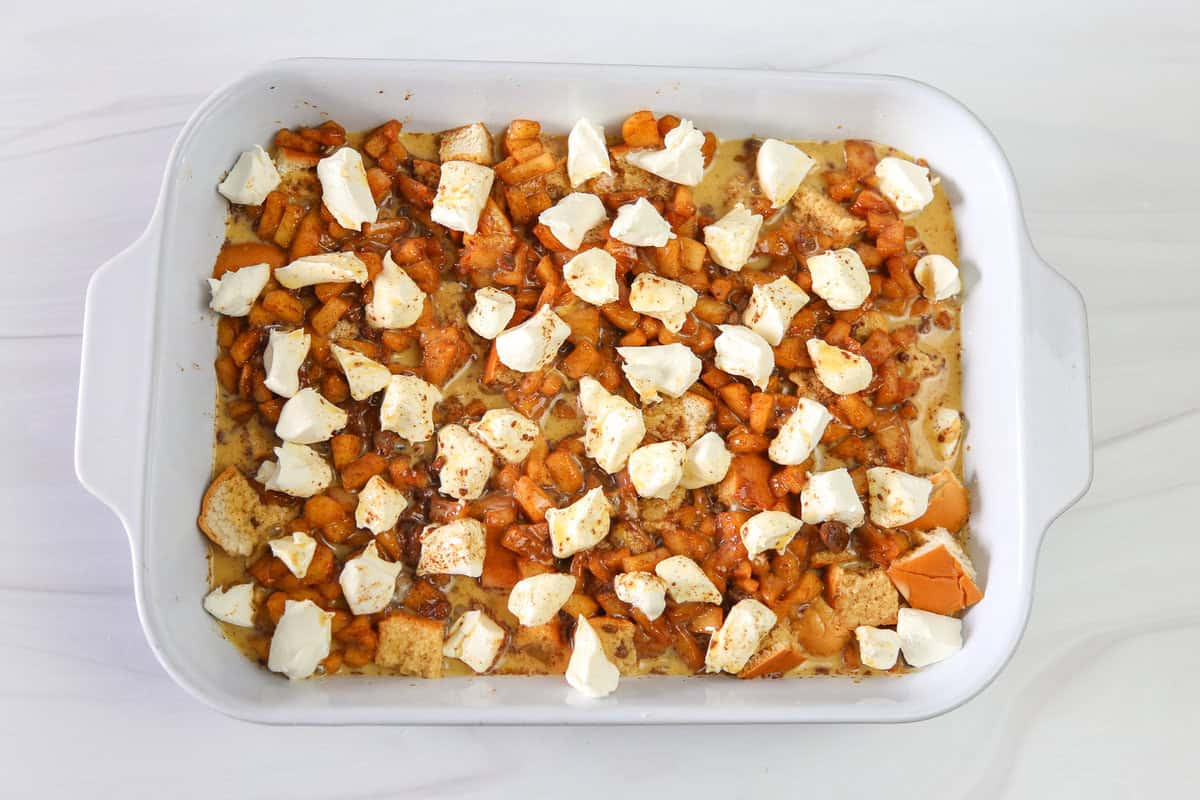 Apple cinnamon french toast casserole ingredients including cubed cream cheese on top ready to be baked.