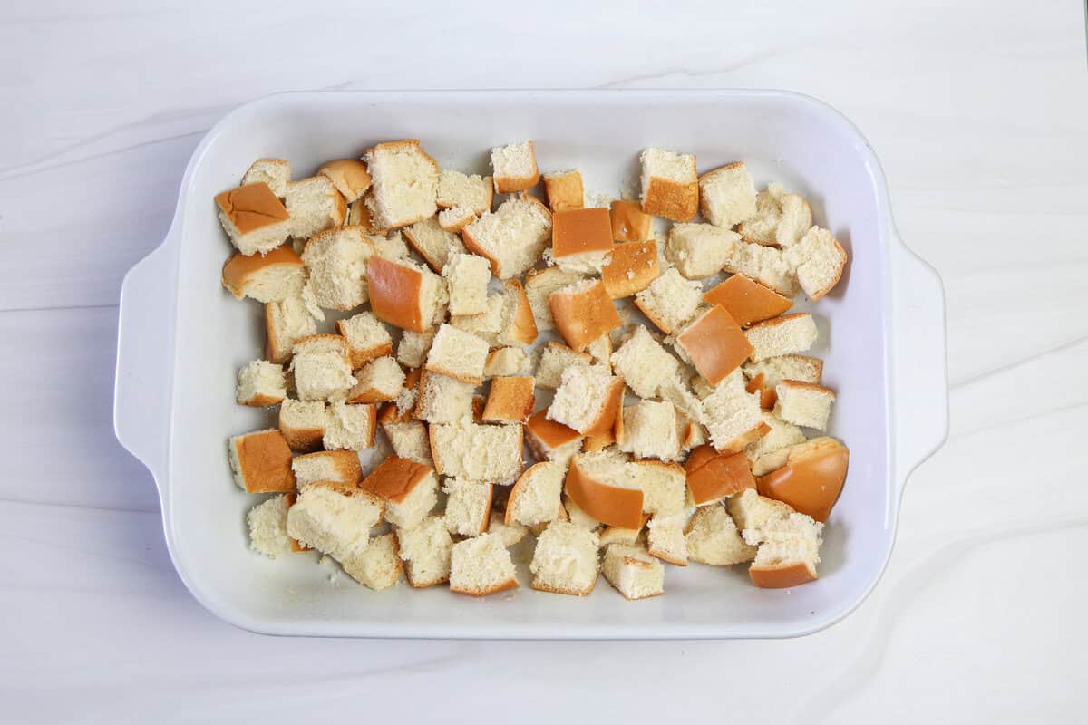 Cubed bread in a white baking dish for apple cinnamon french toast casserole.