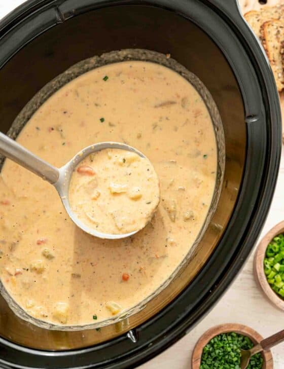 Cheddar and bacon potato soup being ladled out of a crockpot.