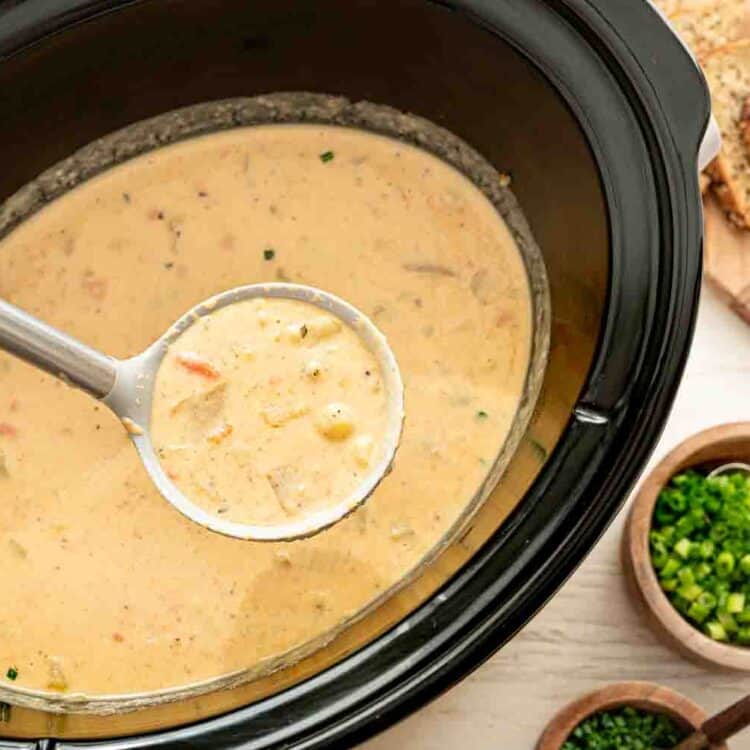 Cheddar and bacon potato soup being ladled out of a crockpot.