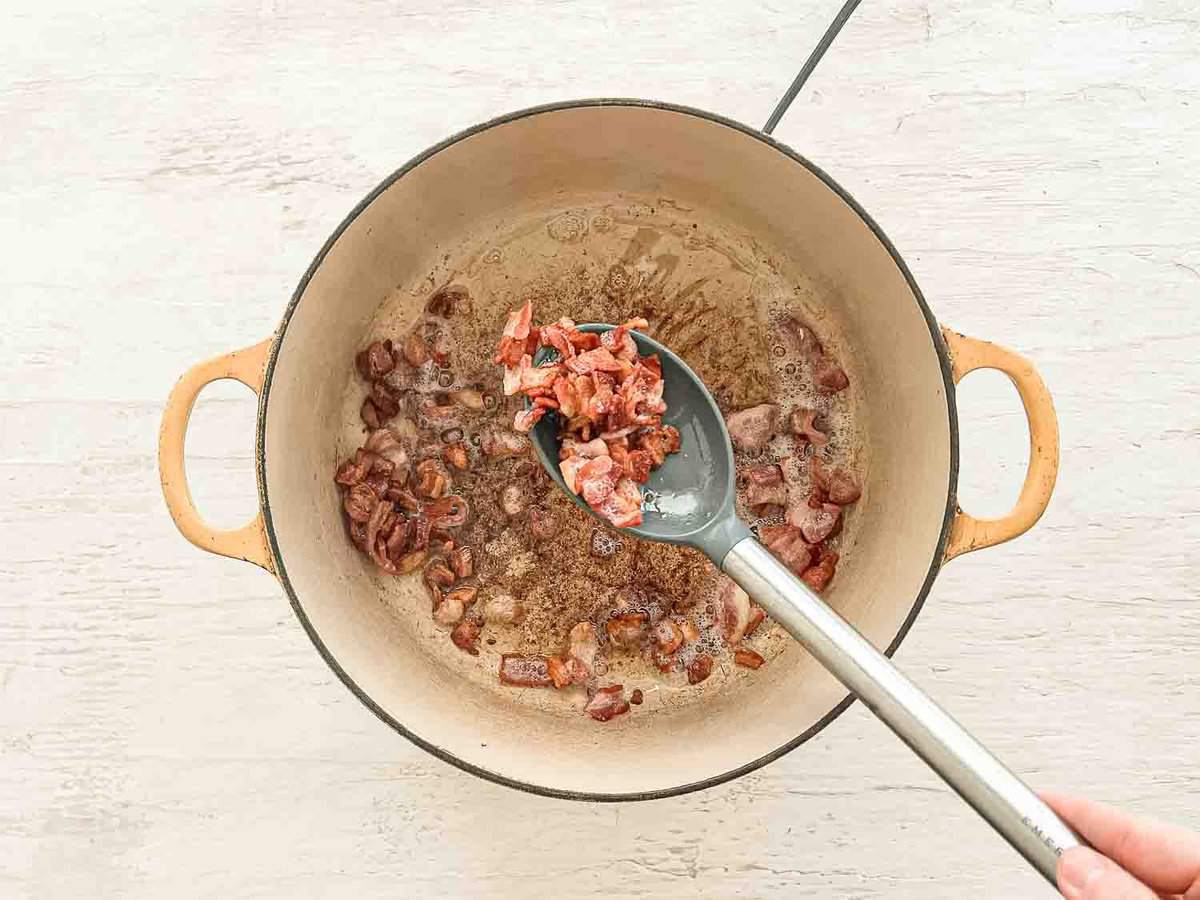 Chopped bacon being cooked in a pot.