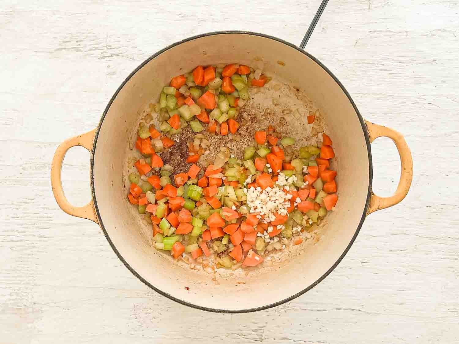 Chopped carrots, celery, onion and garlic sauteeing in a pot.