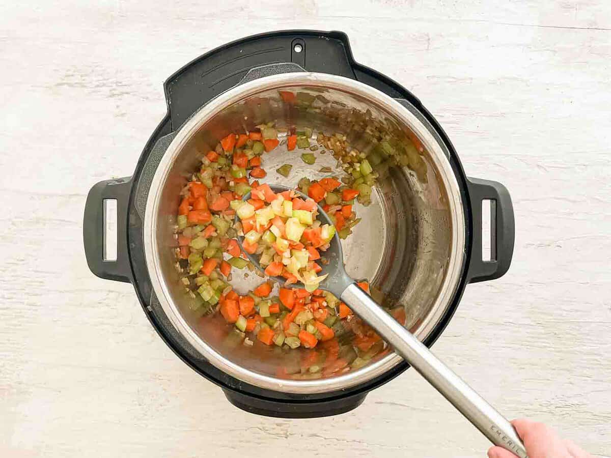 Carrots, celery, and onion being sauteed in an Instant Pot.