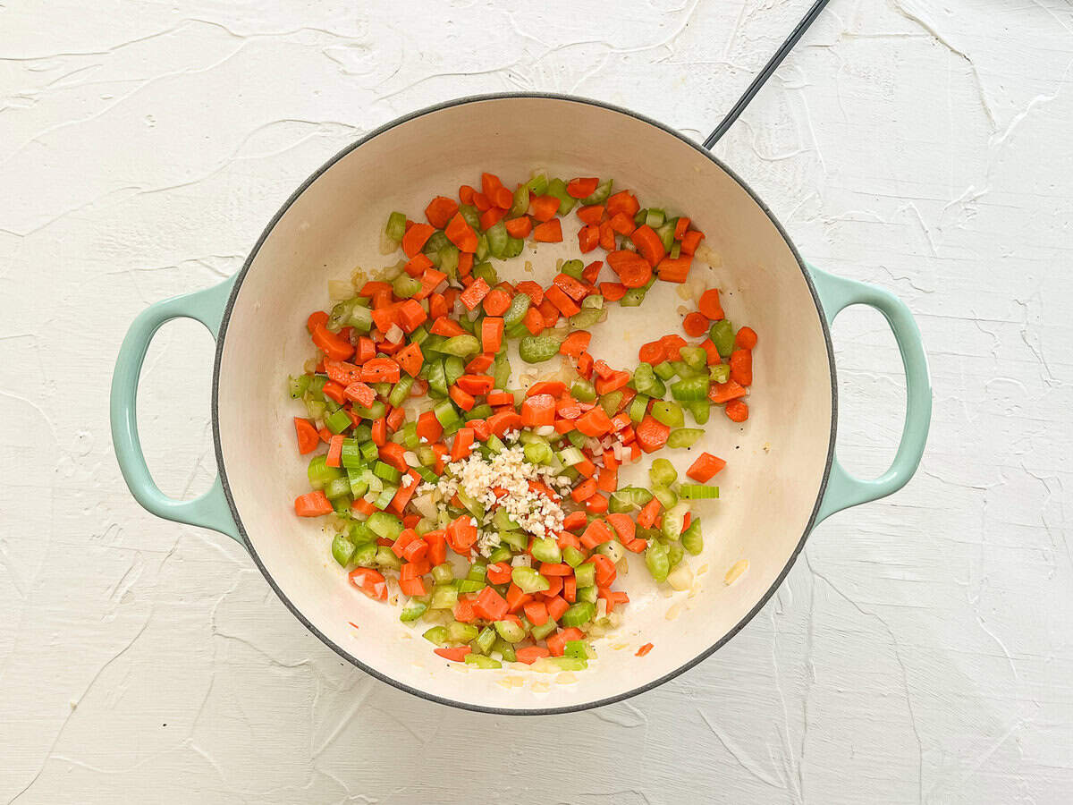 Carrots, celery, onion, and garlic in a pot sauteing in oil.