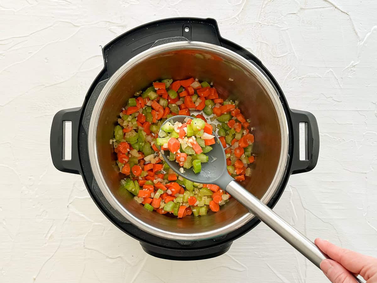 Carrots, celery, onion, and garlic sauteing in an Instant Pot.