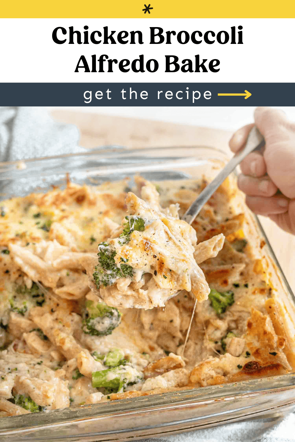 A spoon lifting a serving of chicken broccoli alfredo bake from a square pan.