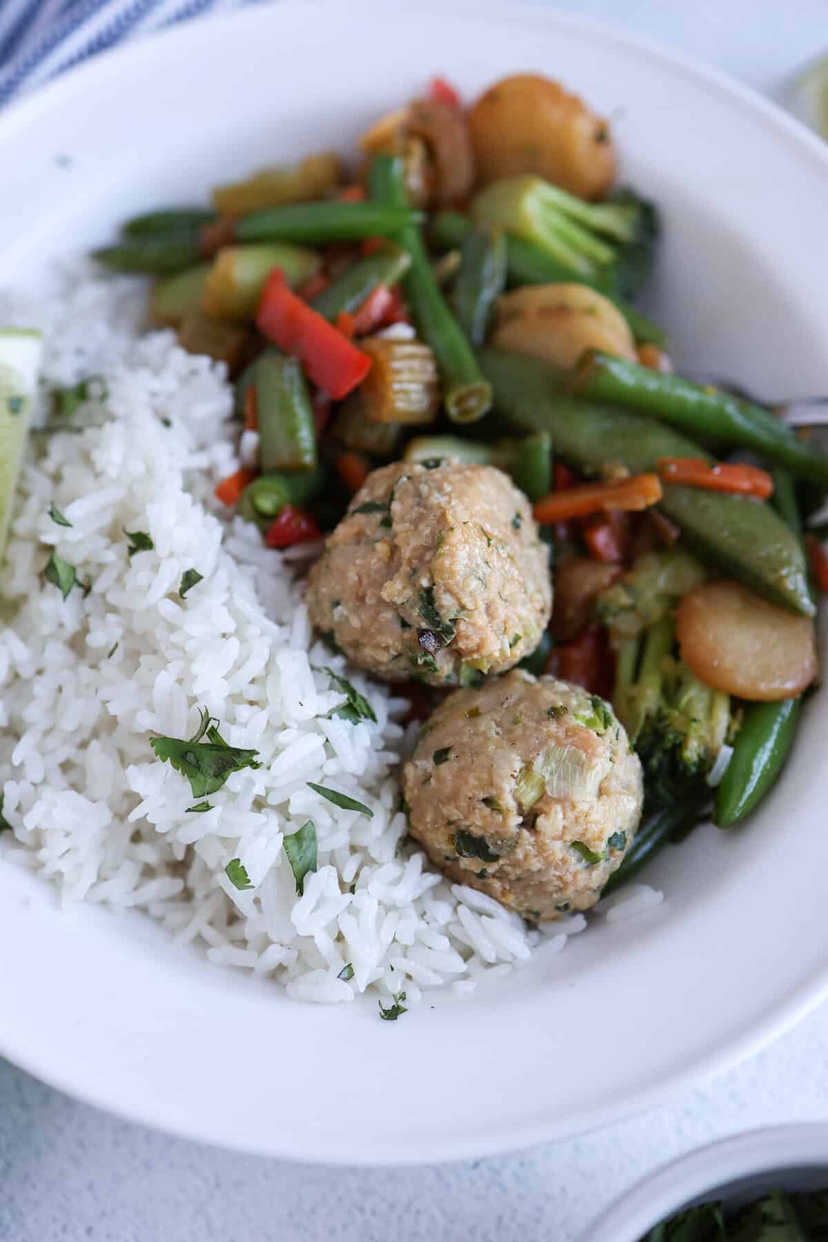 Stir-fry veggies, coconut rice, and turkey meatballs in a bowl.