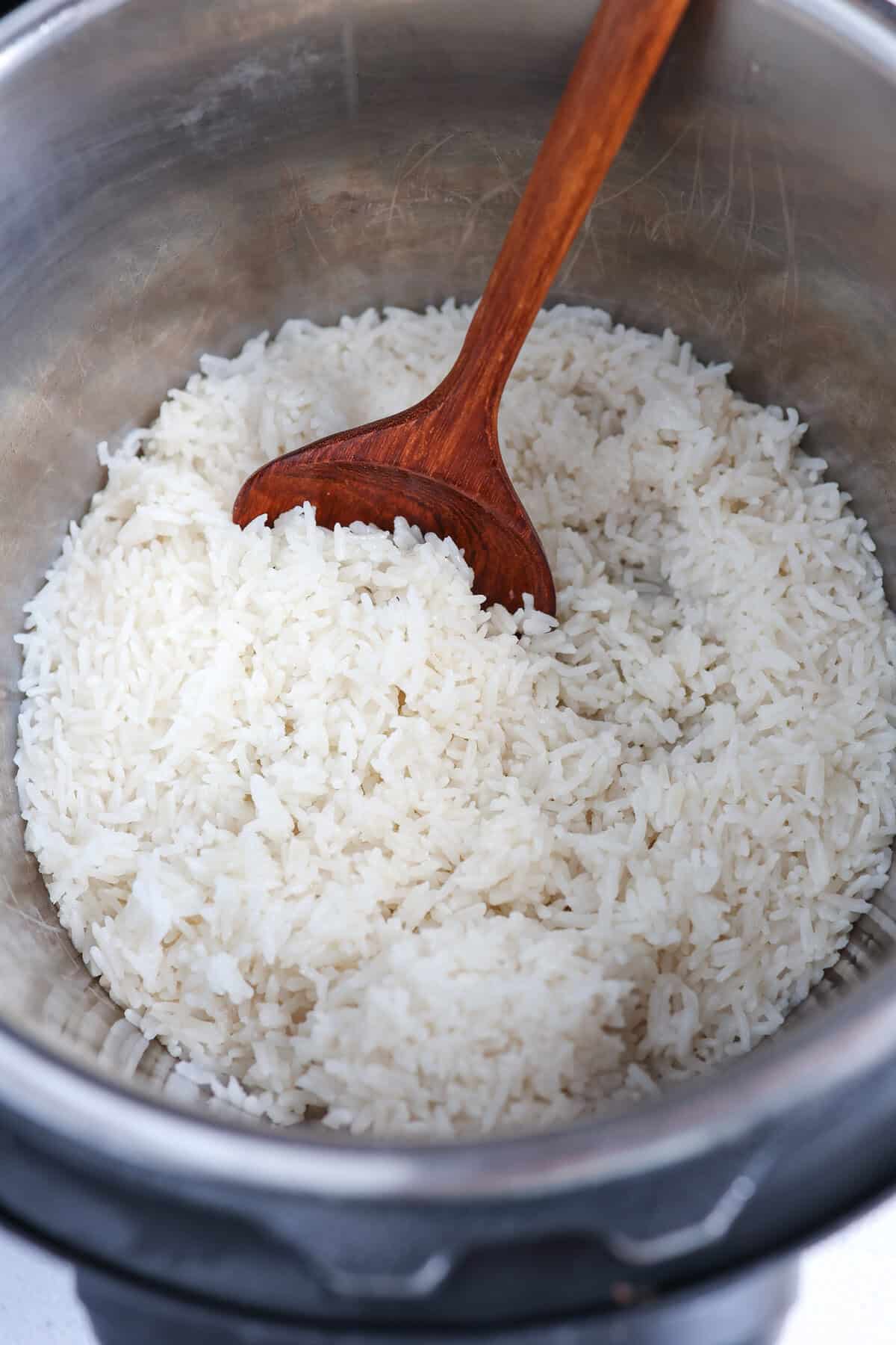 Fully cooked coconut rice in the Instant Pot with a wooden spoon.