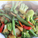 Stir fry veggies in a bowl with a wooden spoon.