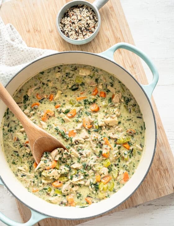 Boursin chicken and wild rice soup in a pot with a wooden spoon ready to serve.