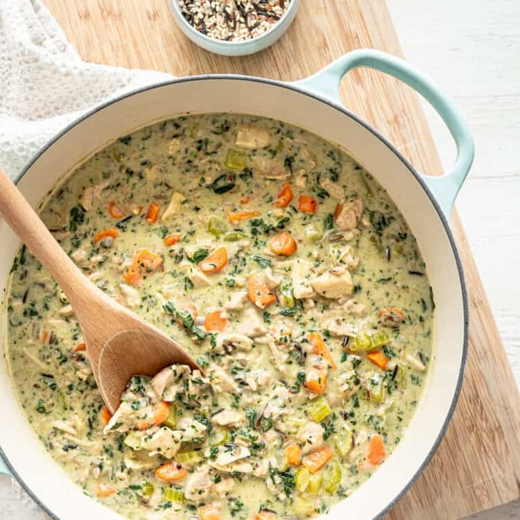 Boursin chicken and wild rice soup in a pot with a wooden spoon ready to serve.