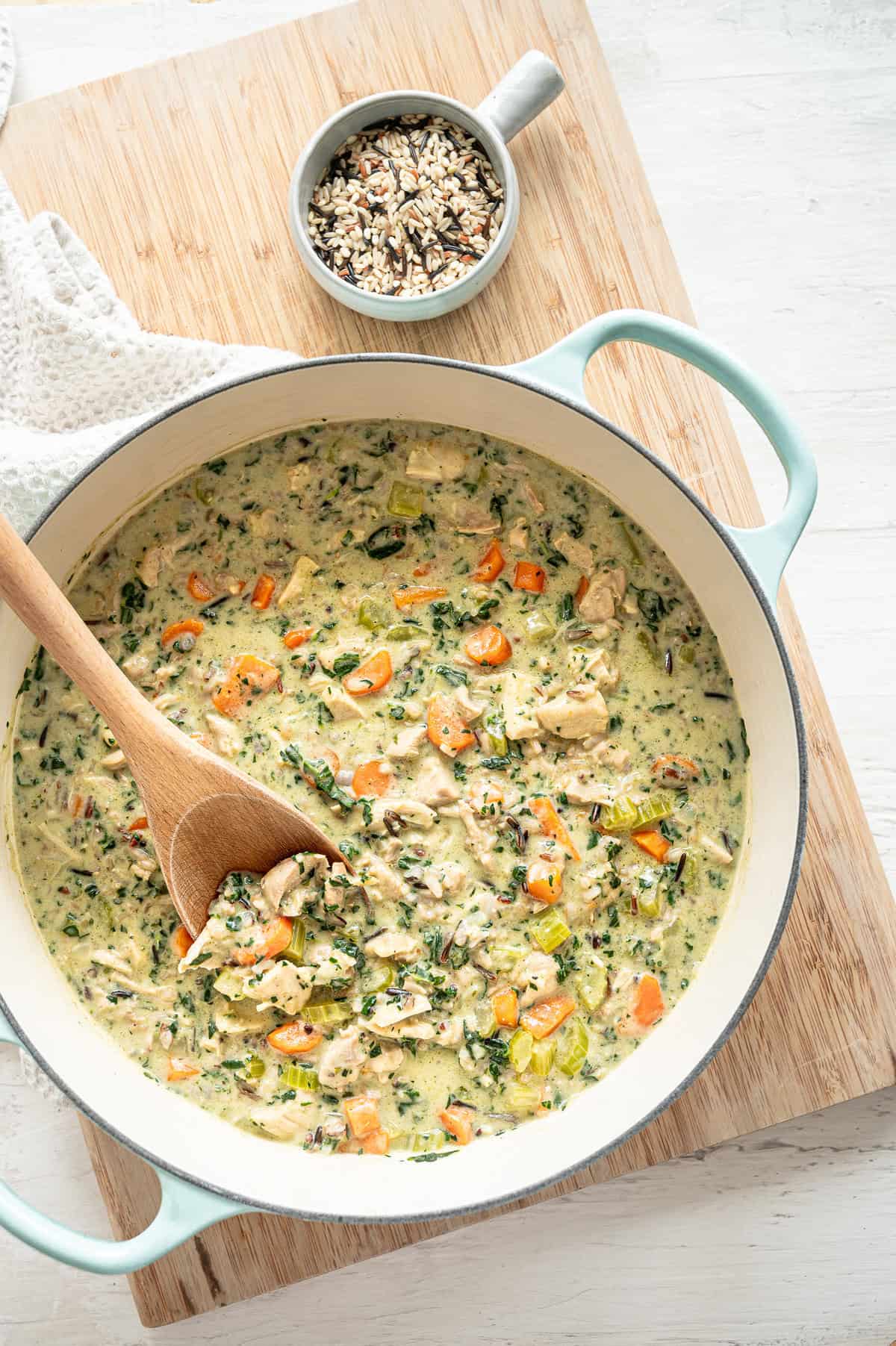 Boursin chicken and wild rice soup in a pot with a wooden spoon ready to serve.