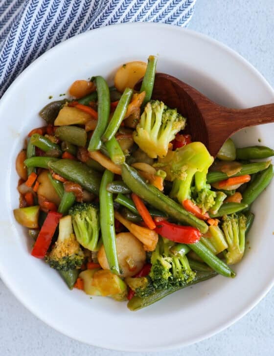 Stir fry veggies in a bowl with a wooden spoon.