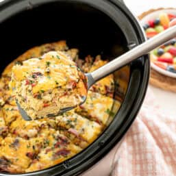 A slice of crockpot breakfast casserole with ham and gruyere on a spatula to be served.