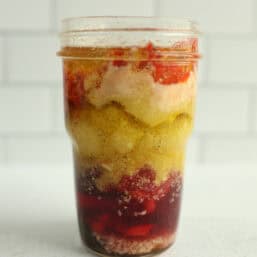 A small mason jar layered with ingredients of homemade Italian Parmesan salad dressing.