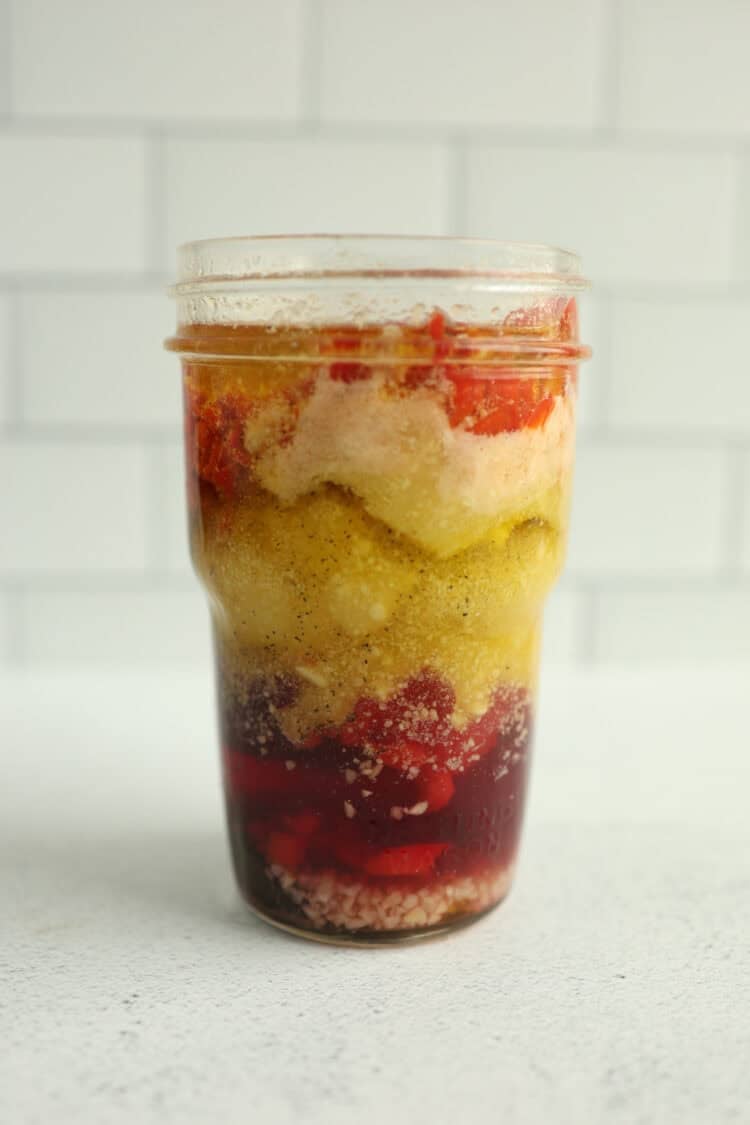 A small mason jar layered with ingredients of homemade Italian Parmesan salad dressing.