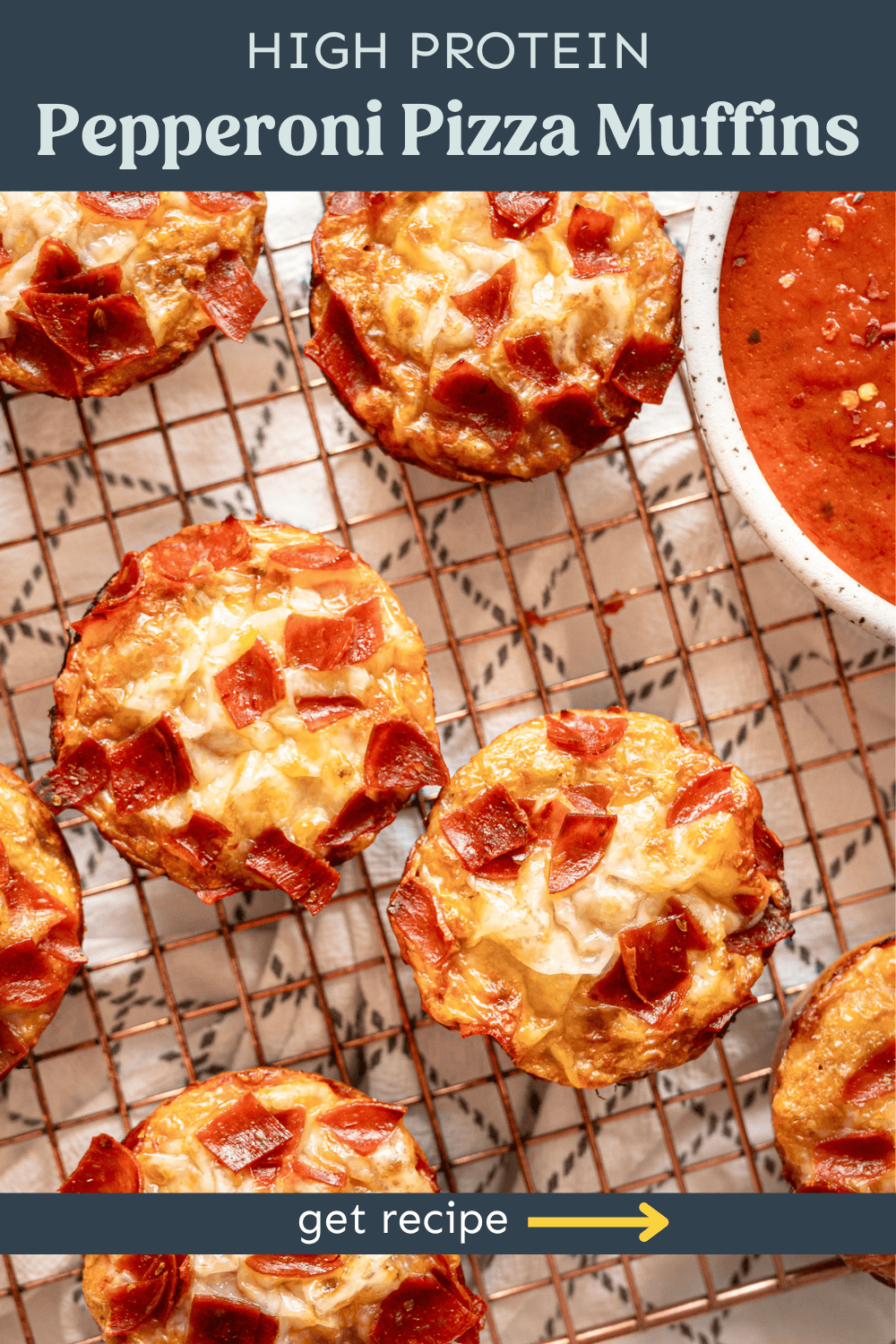 Pepperoni pizza muffins on a baking rack with a bowl of marina sauce.