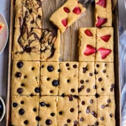 Sheet pan pancake cut into pieces with various toppings on each quadrant.