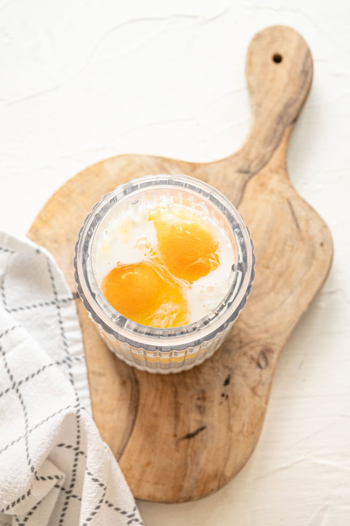 Eggs, milk, and cottage cheese in a glass bowl to be blended.