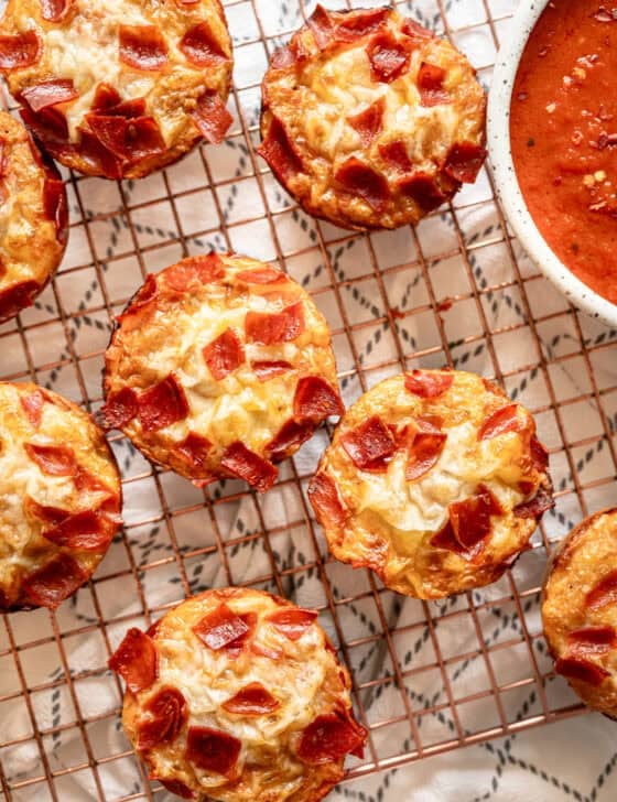 Pepperoni pizza muffins straight from the oven on a cooling rack.