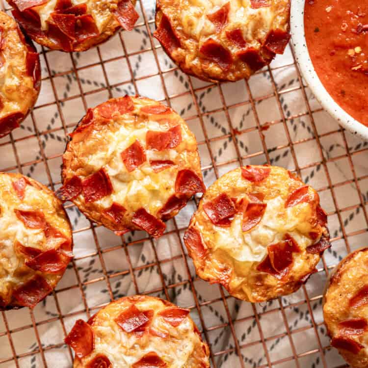 Pepperoni pizza muffins straight from the oven on a cooling rack.